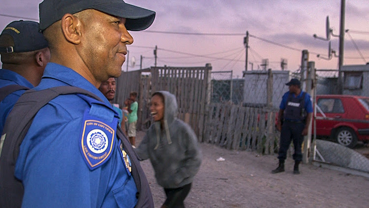 A Metro police officer smiles as a community member makes jokes during a raid in Delft.