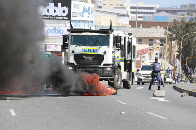 A few protestors run from teargas after burning tyres in Buffalo Street