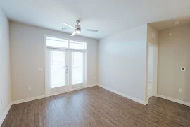 Living room, facing patio door and windows with blinds, with light walls, white trim and doors, and wood plank floors