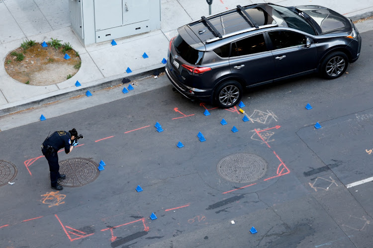 A police evidence technician photographs the crime scene after an early-morning shooting in a stretch of downtown near the Golden 1 Center arena in Sacramento, California, US April 3, 2022.