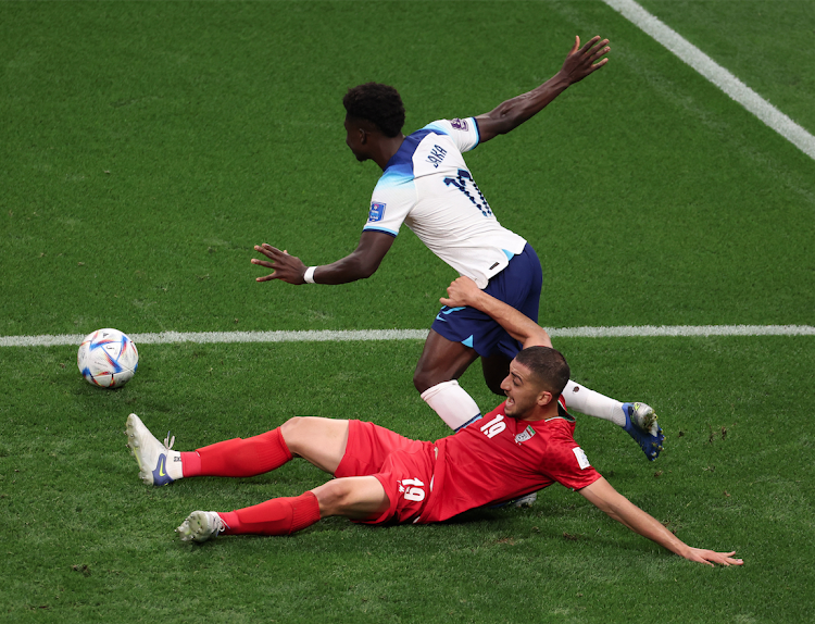 Bukayo Saka of England is tackled by Majid Hosseini of Iran during a Group B match at the Khalifa International Stadium