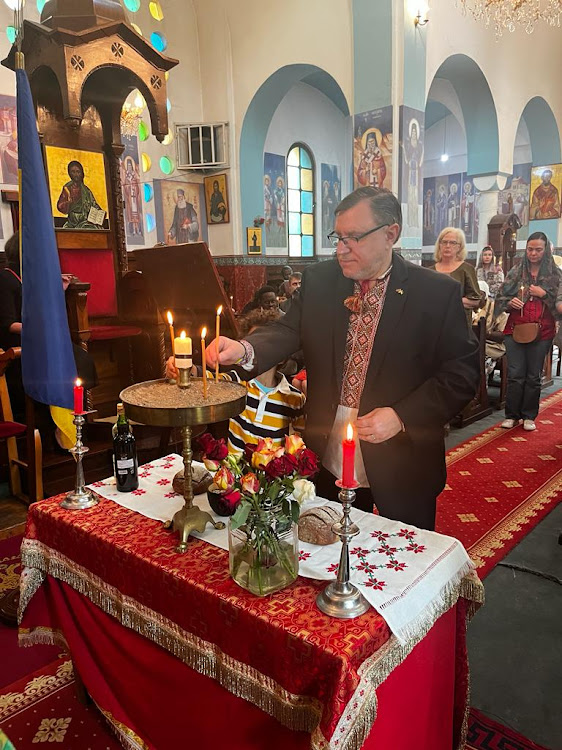 Ukrainian Ambassador to Kenya Andrii Pravednyk places a candle in a sandbox during the commemoration service for the victims of the Holodomor genocide at the Orthodox Patriarchal Cathedral of Sts. Cosmas and Damian, on Valley road, Nairobi on November 25, 2023.