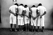 El Salvador. Groep jonge mannen met gezicht tegen een muur, handen geboeid op de rug met de armen aan elkaar