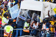 Police protect Kaizer Chiefs coach Arthur Zwane from fans throwing bottles during the DStv Premiership match between SuperSport United and Kaizer Chiefs at Royal Bafokeng Stadium on May 13, 2023 in Rustenburg, South Africa.