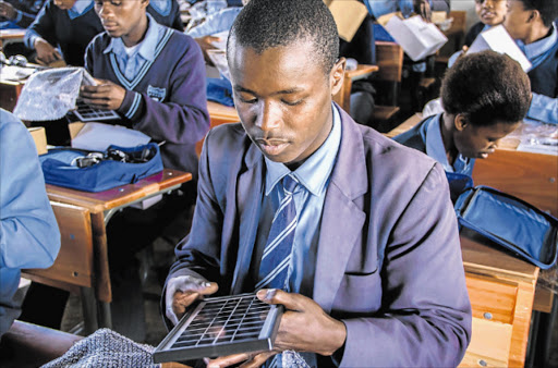 LIGHT MATTERS: Gengqe Senior Secondary school pupil Bongani Mayinana examines his solar kit, after receiving the power pack which will help him access the light he needs to enable him to study at night. He is one of 2500 pupils to receive the kit Picture: SUPPLIED