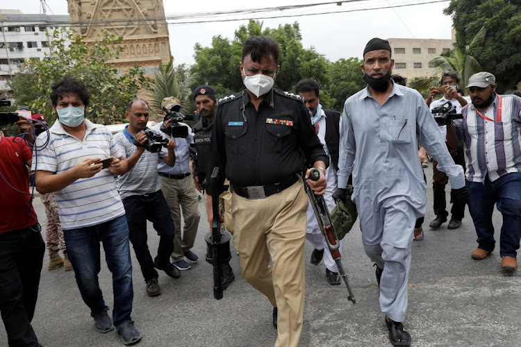 A police officer carries weapons recovered from the site of an attack at the Pakistan Stock Exchange building in Karachi, Pakistan, on June 29 2020.