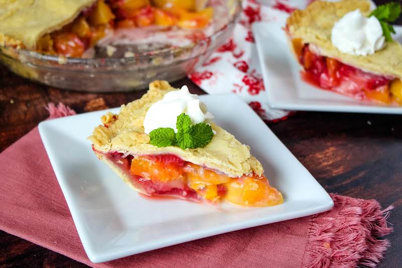 Slice Of Blushing Peach Pie On A Plate.