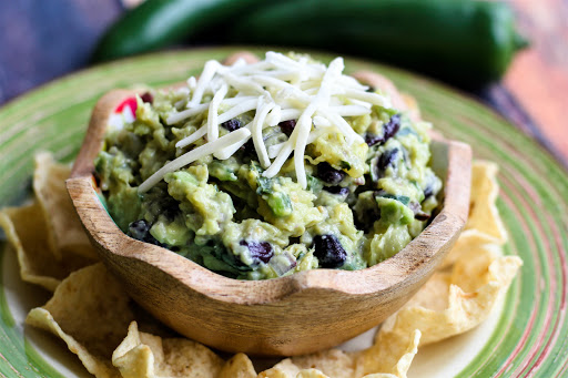 Giddyup Guacamole in a bowl with cheese sprinkled on top.