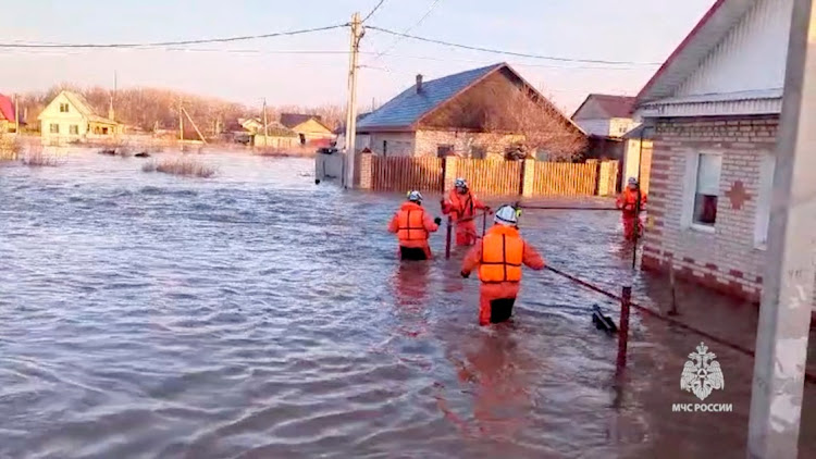 Rescuers make their way on a flooded residential area in the city of Orsk, Russia, April 6, 2024, in this still image taken from video.