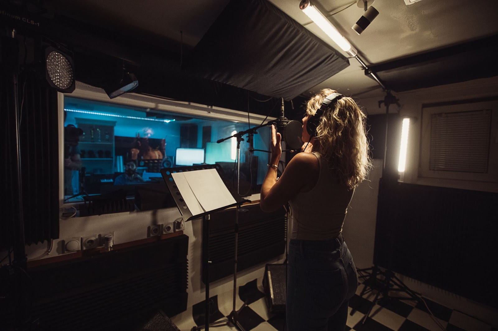 Female musician in a sound booth recording audio. 