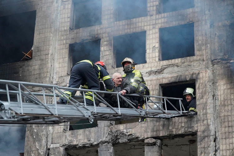 Firefighters use a ladder to evacuate a man from a residential building that was struck, as Russia's attack on Ukraine continues, in Kyiv, Ukraine, in this handout picture released March 14 2022. Picture: STATE EMERGENCY SERVICE, UKRAINE/REUTERS