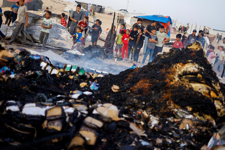 Palestinian children look at the damages while searching for food among burnt debris at the site of an Israeli strike on an area designated for displaced people, in Rafah in the southern Gaza Strip,on Monday. Picture: REUTERS/MOHAMMED SALEM/TPX IMAGES OF THE DAY