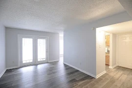 Living room with wood-inspired flooring, gray walls, white trim, two exterior doors with windows, and view of entryway door