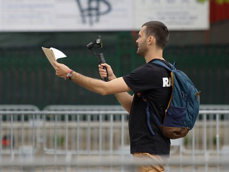 Man recording a video blog in public with a camera.