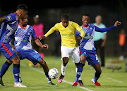 Neo Maema of Mamelodi Sundowns is challenged by Nichlus Lukhubeni, Genino Palace and Clayton Daniels of Maritzburg United in the DStv Premiership match at Harry Gwala Stadium Stadium in Petermaritzburg on March 5 2022.