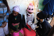 FILE IMAGE: Ansia Kheha's aunt, Artilia Vilanculos, accepts a teddy bear while she mourns the loss of her niece. On her left is another family member, Elsa Nhenjani. 