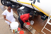 Jojina Kgantshi, left, and Masego Maluleke of Beirut, Mabopane, in Tshwane, collect water from a municipal tanker.