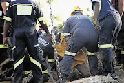 LUCKY ESCAPE: Emergency workers help bring to the surface one of 11 illegal miners trapped in a mine in Benoni, east of Johannesburg yesterday.