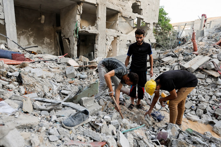 Palestinians men look through debris as people gather at the scene where senior commander of Islamic Jihad militant group Khaled Mansour was killed in Israeli strikes, in Rafah in the southern Gaza Strip, August 7, 2022.