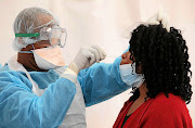 A health official kitted out in full personal protective gear tests a woman in the Western Cape, which has recorded two-thirds of the country's coronavirus infections. Picture: 