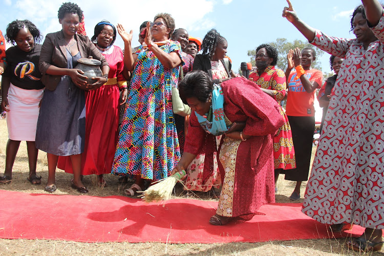 Homa Bay woman reprsesentative Gladys Wanga sweeps a carpet as a symbol of clean leadership during her endorsement on December 12, 2021.