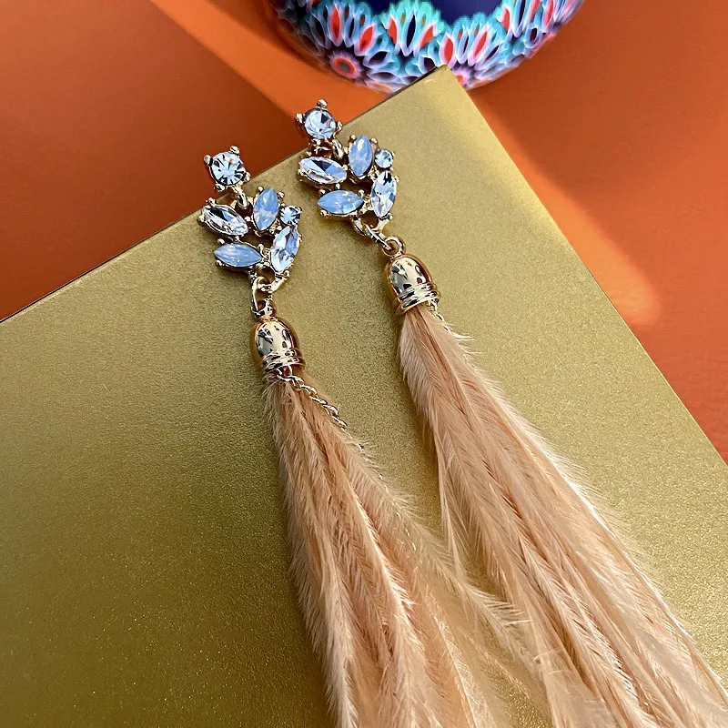 Boucles d'oreilles argentées à pampilles de plumes incrustées de strass, élégantes et scintillantes, parfaites pour rehausser votre style.