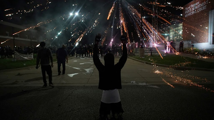 Fireworks explode over a protester with his hands up during a protest against the death in Minneapolis police custody of African-American man George Floyd, in Ferguson, Missouri, US, on May 30 2020.