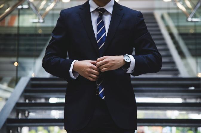 A person in a suit and tie shaking hands

Description automatically generated with low confidence