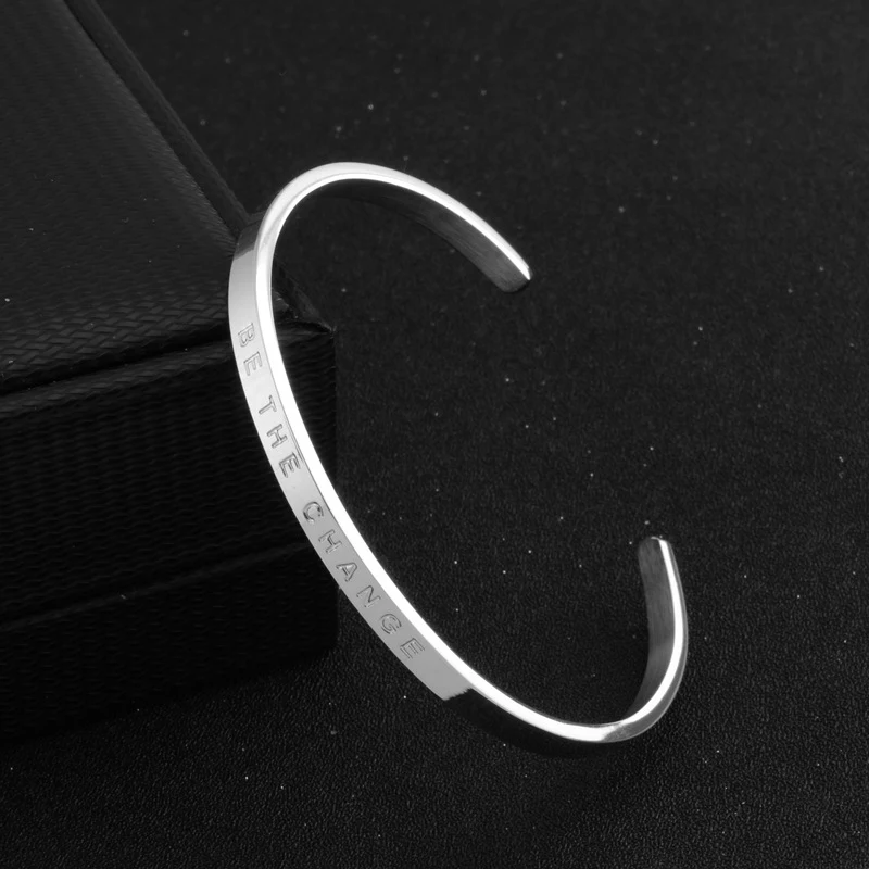 Pulseira de moda BETHECHANGE em aço titânio com extremidade aberta. Um acessório elegante para inspirar e fazer a diferença.