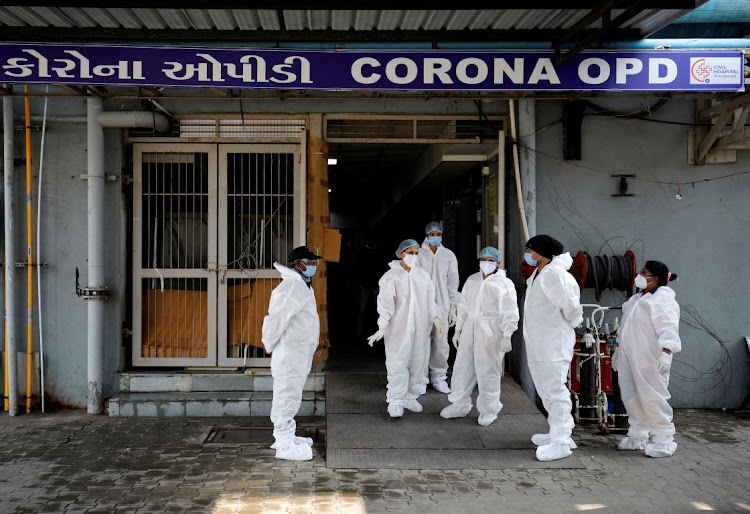 Healthcare workers wearing personal protective equipment (PPE) stand at the entrance of a coronavirus disease (Covid-19) hospital in Ahmedabad, India.