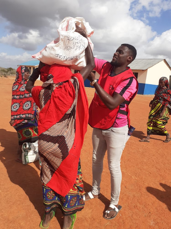 Kenya Red Cross official assists a Garsen resident during a food distribution exercise in the region.