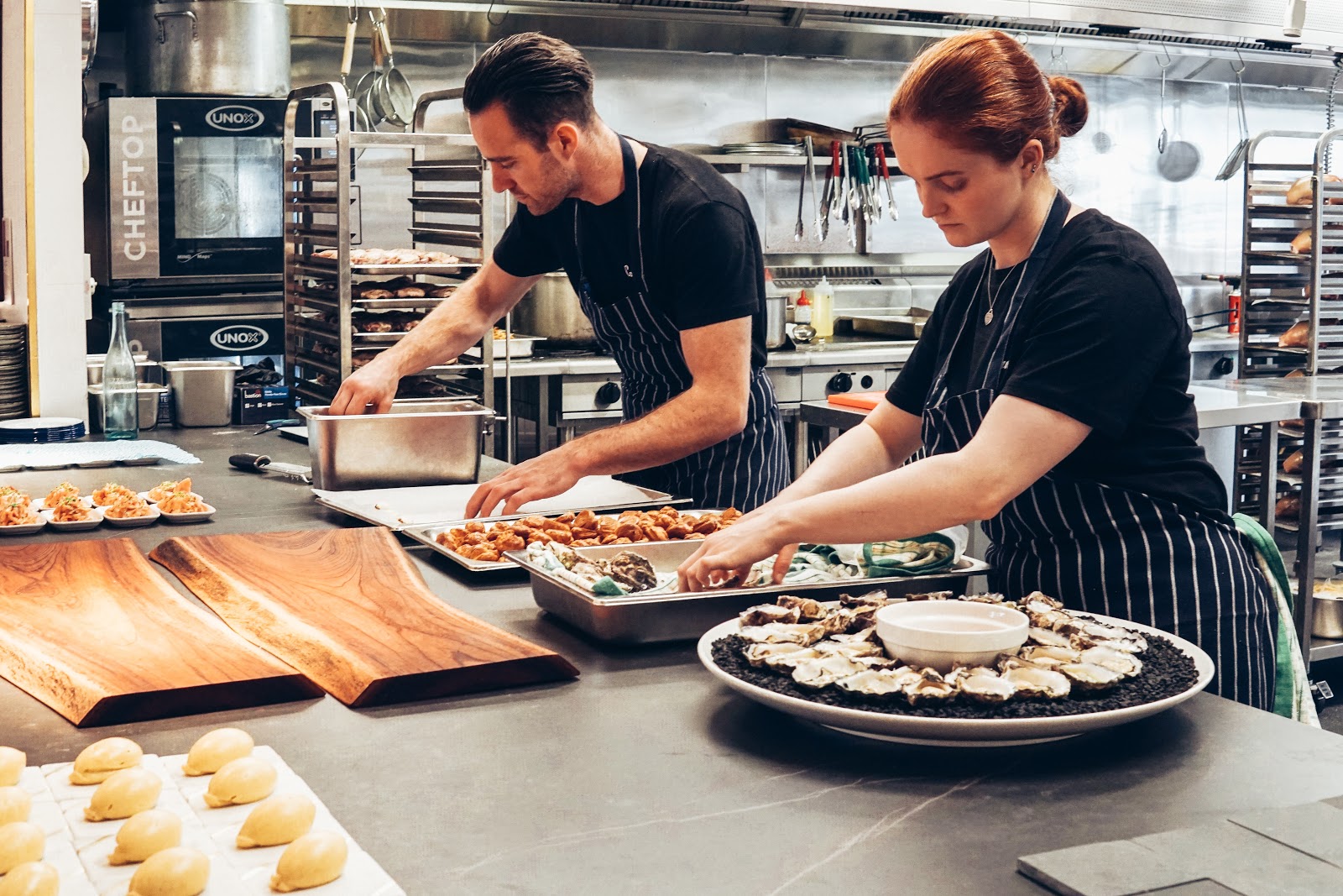 Workers cooperate to prepare food in a professional kitchen.