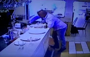 A man stealing a cellphone at a busy restaurant.