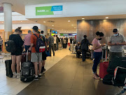 Passengers queue at the Kulula and British Airways counter at Cape Town International Airport after flights were grounded for safety reasons on March 12 2022.