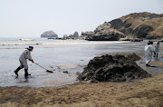 Workers clean up an oil spill caused by abnormal waves, triggered by a massive underwater volcanic eruption half a world away in Tonga, at the Peruvian beach in Ventanilla, Peru, January 18, 2022. 