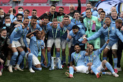 Manchester City players celebrate with the League Cup trophy, their fourth in a row. 