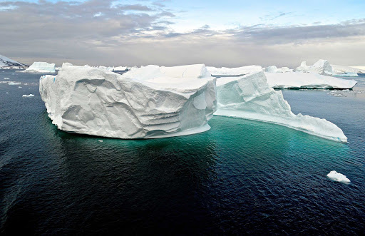 Turquoise waters lap against an iceberg on a Lindblad Expeditions cruise to Antarctica.