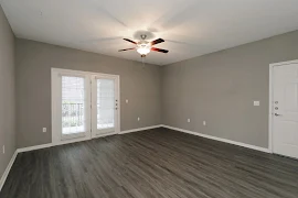 Apartment entryway open to the living area with wood-inspired flooring, a ceiling fan, and doors to the outdoor patio