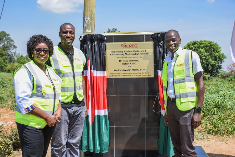 REREC CEO Dr Rose Mkalama and Board Directors Milton Lucheri and Philip Cherige unveil a plaque to commemorate the commissioning of four rural electrification projects in Teso South Constituency on March 20, 2024.