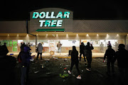 A Dollar Tree store that was looted has its sprinklers turned on as protesters gather outside Brooklyn Center Police Department a day after Daunte Wright was shot and killed by a police officer, in Brooklyn Center, Minnesota, US, on April 12 2021.