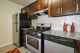 Kitchen with dark wood-inspired cabinets, stainless steel appliances, and gray backsplash