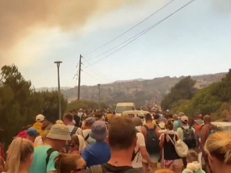 Crowds wait to be evacuated as wildfires burn in this video screengrab obtained from social media, in Rhodes, Greece, July 22, 2023.