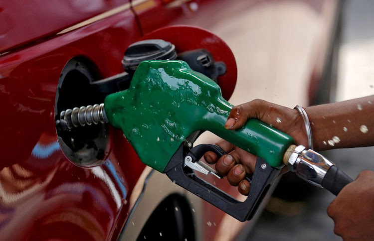 A worker holds a nozzle to pump petrol into a vehicle at a fuel station in Mumbai, India, May 21, 2018.