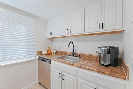 Kitchen with white cabinets, stainless steel appliances, tan countertops, and a subway tile backsplash 