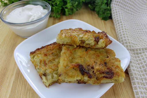 Potato kugel cut into squares with sour cream on the side.