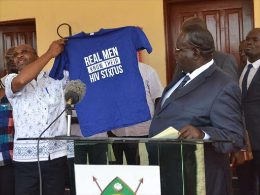 An anti-HIV crusader displays a T-shirt with a message that promotes testing for HIV in Homa Bay as Governor Cyprian Awiti looks on, February 9, 2018. /FILE