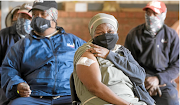 Western Cape health MEC Nomafrench Mbombo with farmers at a pop-up vaccination bus in the province.  

