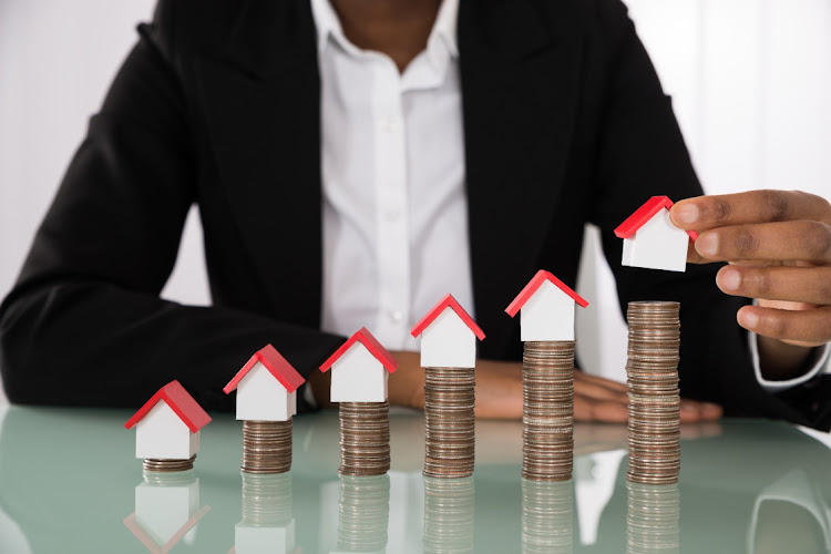 Businesswoman Arranging House Model On Stacked Coins. Picture: 123RF.com