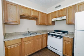 Kitchen featuring wood cabinets, white appliances, and stone inspired countertops