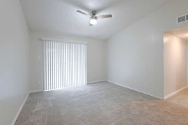 Empty apartment living room with carpet, white walls, with a vaulted ceiling and ceiling fan, 